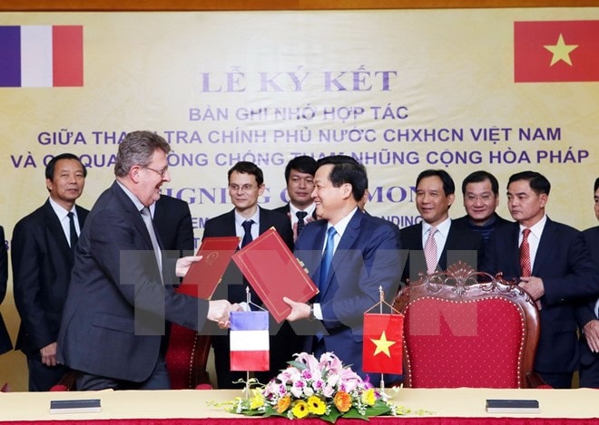 Tổng Thanh tra Chính phủ Lê Minh Khái và Giám đốc Cơ quan Phòng chống tham nhũng Cộng hòa Pháp Charles Duchanie trao đổi biên bản ký kết hợp tác. (Ảnh: Nguyễn Dân/TTXVN)