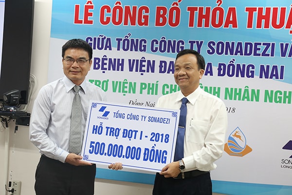 Ông Phan Đình Thám (bên trái) đại diện Tổng công ty Sonadezi trao biểu trưng hỗ trợ cho lãnh đạo Bệnh viện Đa khoa Đồng Nai