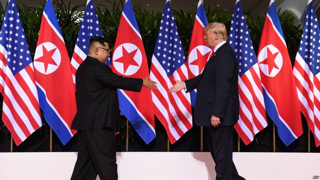 Tổng thống Mỹ Donald Trump (phải) và Lãnh tụ Triều Tiên Kim Jong Un (trái) chìa tay ra bắt tại một hội nghị thượng đỉnh lịch sử của hai nước trên đảo Sentosa của Singapore, ngày 12 tháng 6, 2018.