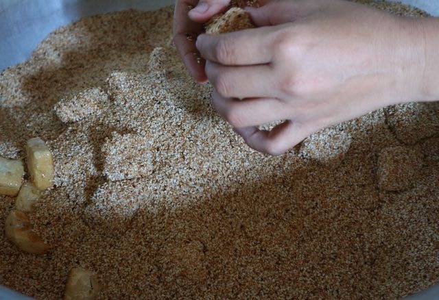 Tiếp theo là lăn mè, mè phải được áo đều, lớp mè phủ kín khắp lớp bánh. Các nguyên liệu được lựa chọn kỹ càng, chính gốc địa phương