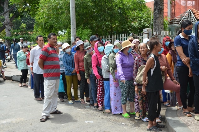 Người nhà và bệnh nhân xếp hàng chờ nhận suất cơm từ thiện trước cổng bệnh viện.