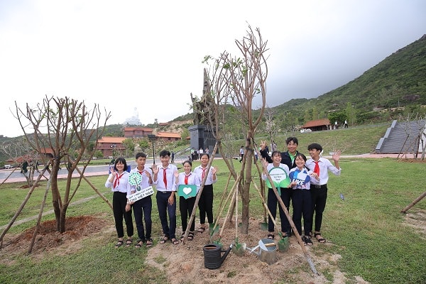 Các em học sinh chụp hình lưu niệm bên những cây xanh vừa được trồng trong chương trình Quỹ 1 triệu cây xanh cho Việt Nam.