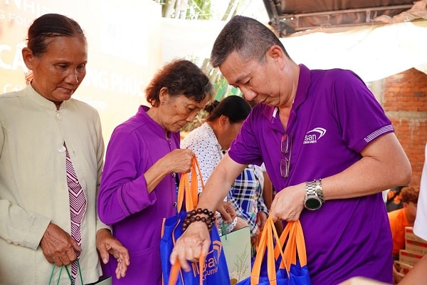 Nhân viên công ty Cổ phần Hàng Tiêu Dùng Masan trao quà cho các em học sinh và bà con