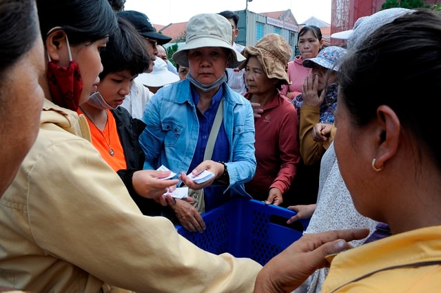 Thành viên của các nhóm từ thiện vừa nhận phiếu vừa phát cơm cho người nhà và bệnh nhân tại cổng bệnh viện Nhân dân 115 TP. HCM.