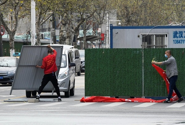 Người dân thành phố Vũ Hán dỡ các tấm chắn phong tỏa trên đường phố. Ảnh: Reuters