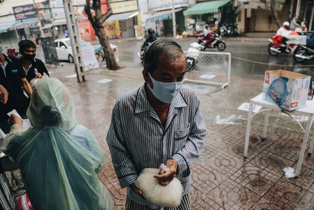 Mỗi người nhận được gạo xong nhanh chóng ra về dù trời đang mưa để tránh tình trạng tập trung đông người.