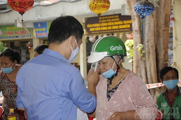 Trước khi vào mua hàng, người dân được đo thân nhiệt...