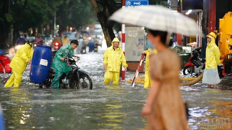 Công nhân Xí nghiệp thoát nước Hà Nội số 1 cho biết anh phải canh tấm chắn hố ga suốt quá trình mưa giúp không bị sóng đánh từ ôtô có thể gây đổ.