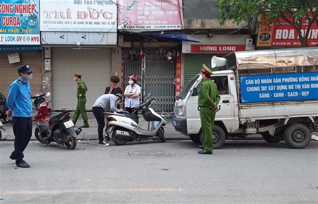 Tổ công tác phường Đồng Nhân (quận Hai Bà Trưng, Hà Nội) xử phạt các trường hợp vi phạm không đeo khẩu trang ra đường. Ảnh: TTXVN