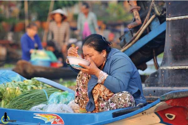 Vội vã đi chợ từ tinh mơ sớm, người dân lao động ăn vội tô bún rồi lại đẩy thuyền đi bán hàng.