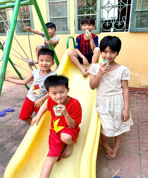 Em Lan Thương (áo đầm trắng) cùng các bạn quây quần uống sữa bên chiếc xích đu trong trung tâm.