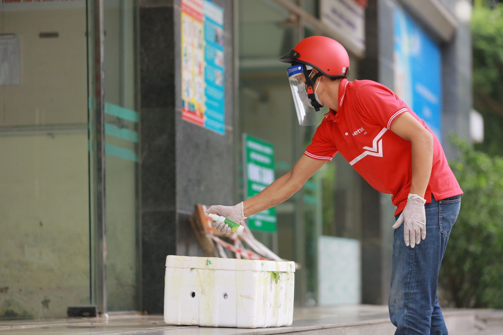 Nhân viên giao hàng Viettel Post cần đặt hàng hóa tại bàn của các điểm chốt dịch, xịt dung dịch khử khuẩn vào hàng, chụp ảnh xác nhận với khách hàng thông qua ứng dụng, sau đó lùi lại 2 bước