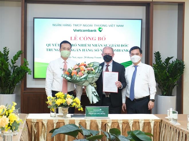 Ông Phạm Quang Dũng - UV BCH Đảng bộ Khối DNTW, Bí thư Đảng ủy, Chủ tịch HĐQT Vietcombank (ngoài cùng bên trái) và ông Nguyễn Thanh Tùng – Phó TGĐ phụ trách BĐH Vietcombank (ngoài cùng bên phải) trao quyết định và hoa chúc mừng tân Giám đốc Trung tâm ngân hàng số Vietcombank