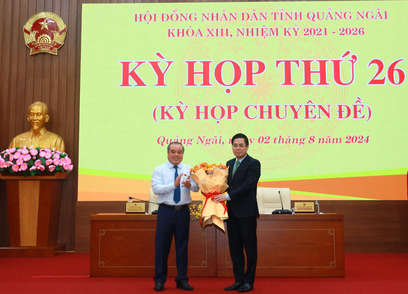 Ông Trần Hoàng Tuấn - Phó Chủ tịch Thường trực UBND tỉnh (bên trái) tặng hoa chúc mừng ông Nguyễn Hoàng Giang - Tân Chủ tịch UBND tỉnh Quảng Ngãi. Ảnh: Viên Nguyễn