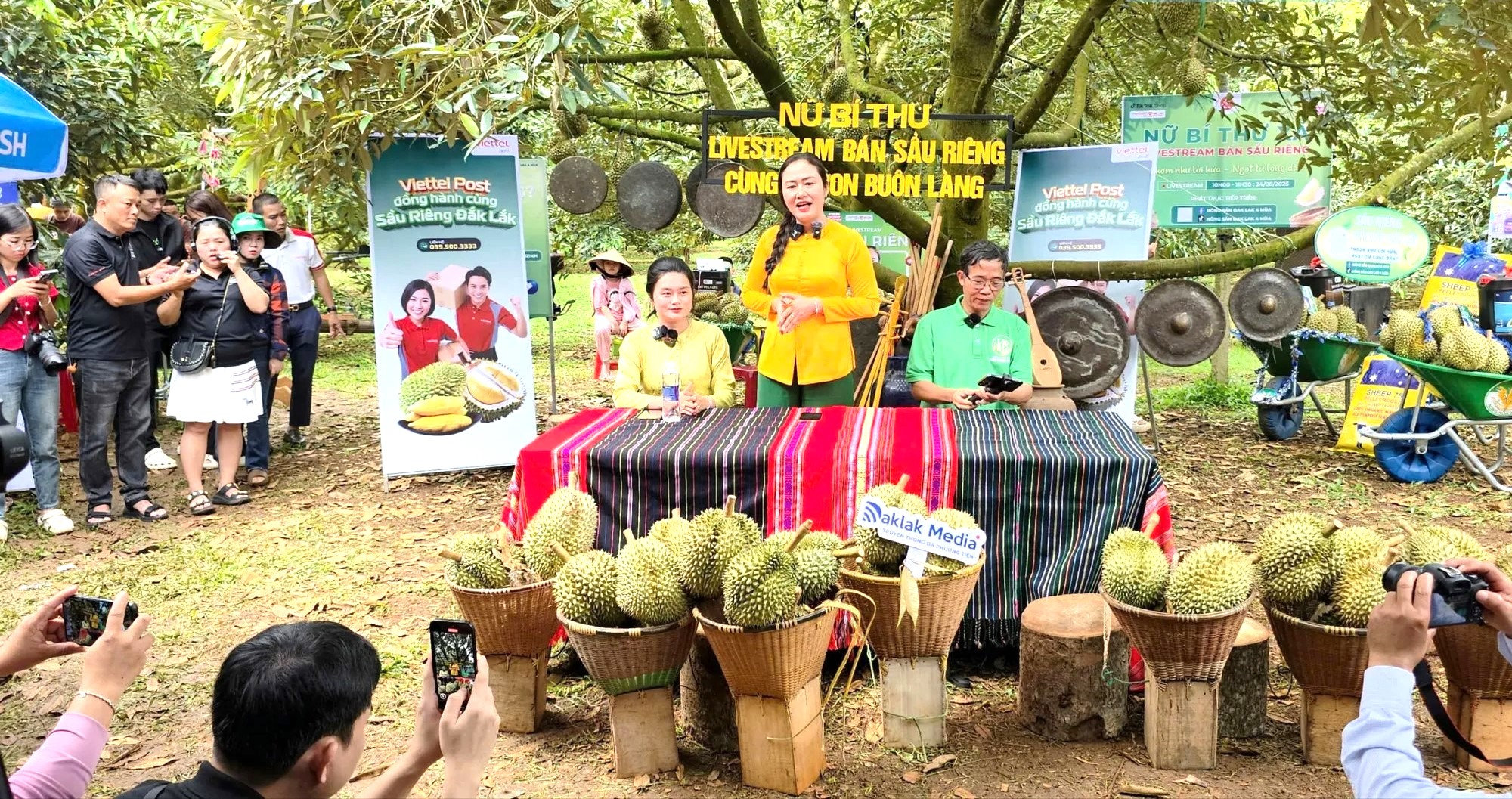 Bà Ngô Thị Minh Trinh , Bí thư Đảng ủy xã Ea Knuếc đứng giữa, cùng bà con buôn làng livestream bán sầu riêng tại vườn.