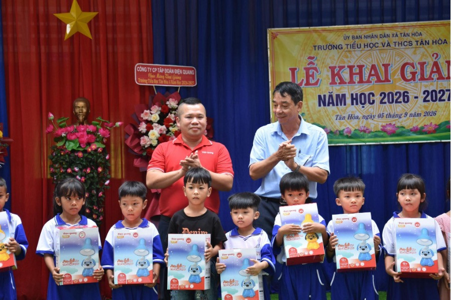 Ông Dương Hồ Thắng – Phó Tổng Giám đốc Điện Quang (áo đỏ, bên trái) cùng đại diện địa phương trao tặng các phần quà học tập cho học sinh nhân dịp khai giảng năm học 2026–2027.
